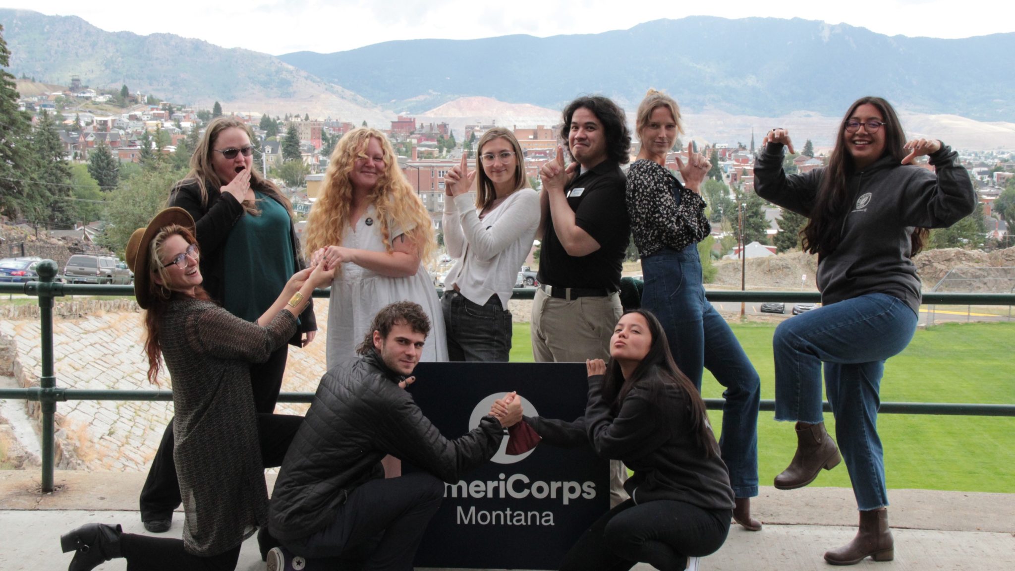 AmeriCorps members strike funny pose in front of AmeriCorps Montana sign