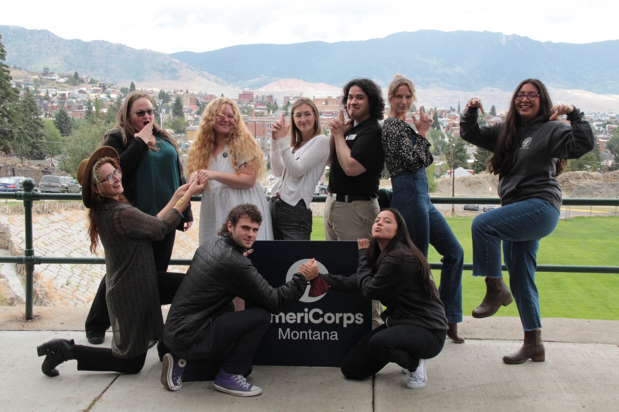 AmeriCorps members strike funny pose in front of AmeriCorps Montana sign