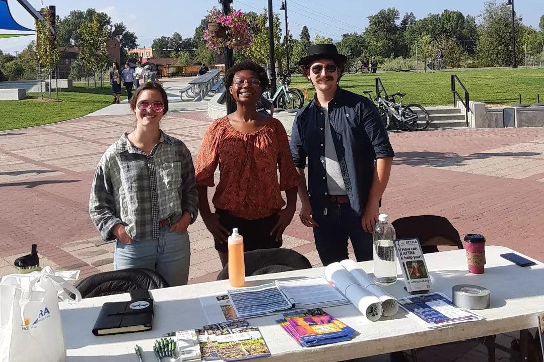 Three AmeriCorps members standing outside at a table with brochures.