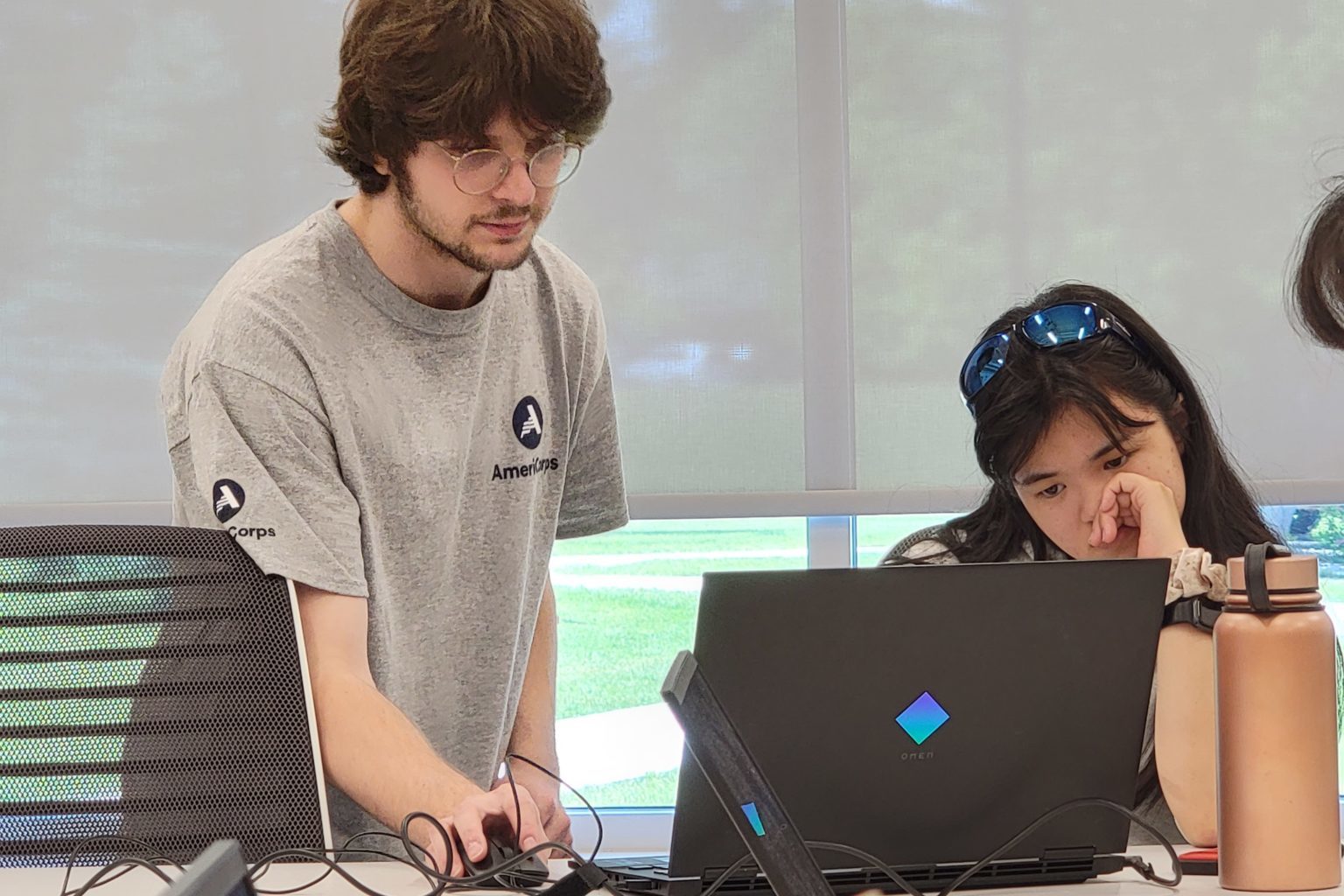 AN AmeriCorps member helping a student at a laptop.