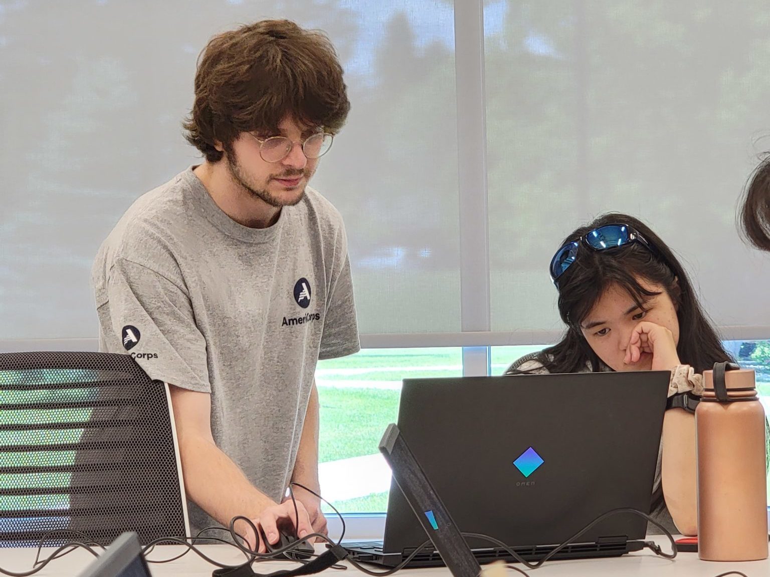 An AmeriCorps member at a laptop with a student.