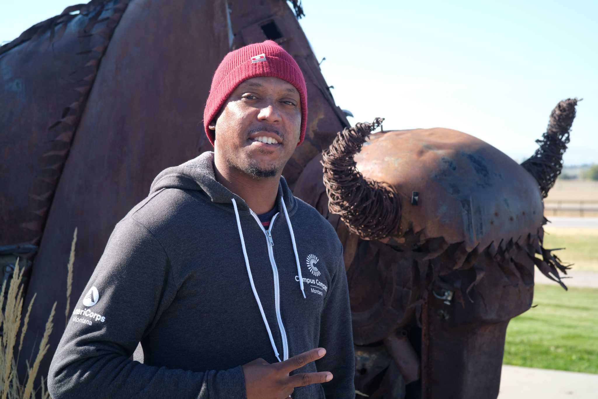 AmeriCorps member standing in front of a metal bison statue.