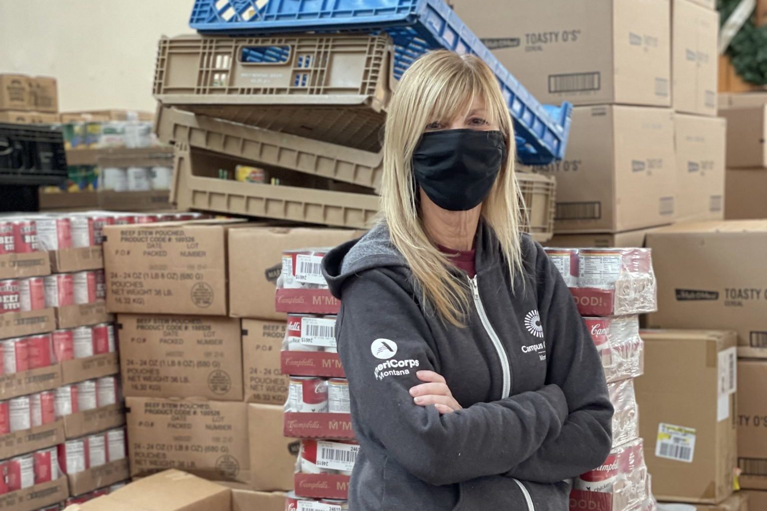 An AmeriCorps member standing in front of boxes of donated food.