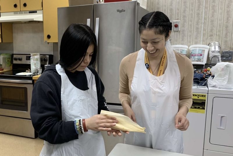 An AMeriCorps member showing a high school student how to make tamales.